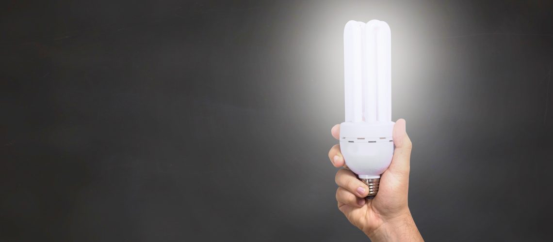 Man holding an illuminated eco-friendly light bulb